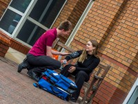 Man taking blood pressure of woman sat on a bench