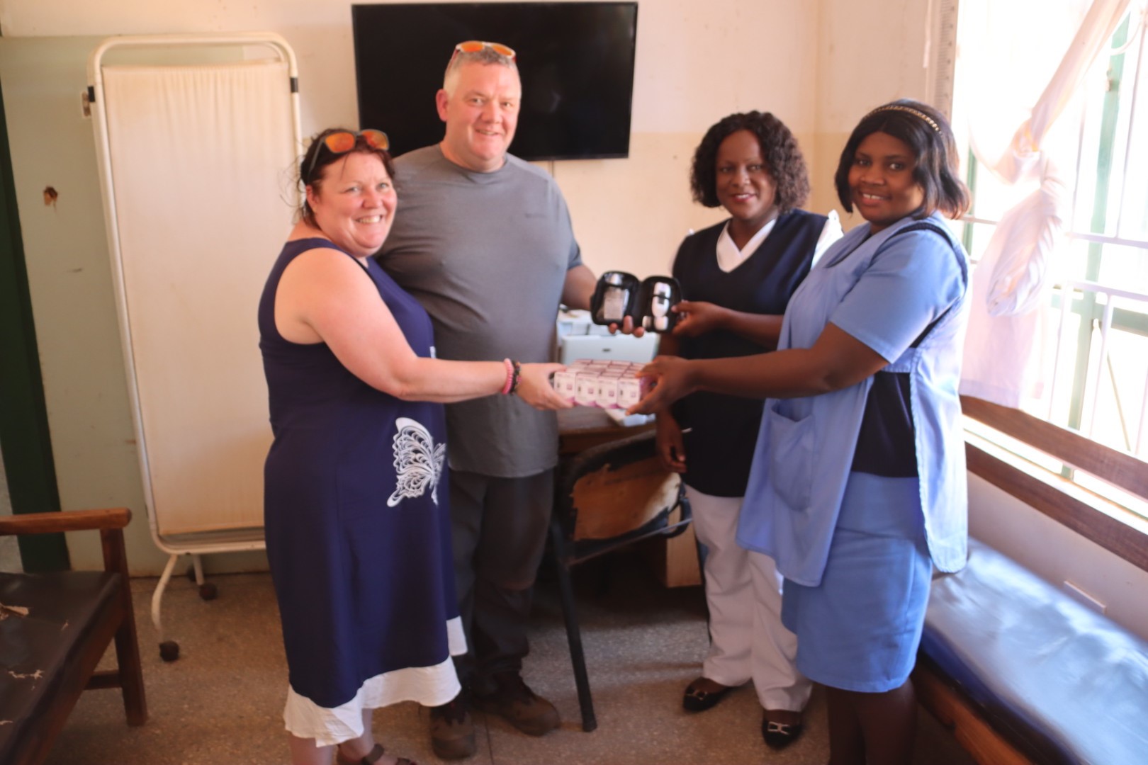 Two individuals handing over medical equipment to Zambian hospital representatives