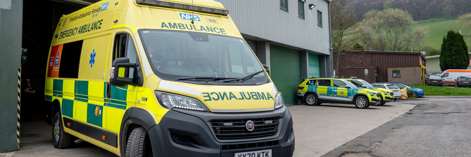 Emergency ambulance parked in the forefront with emergency response vehicles in the background
